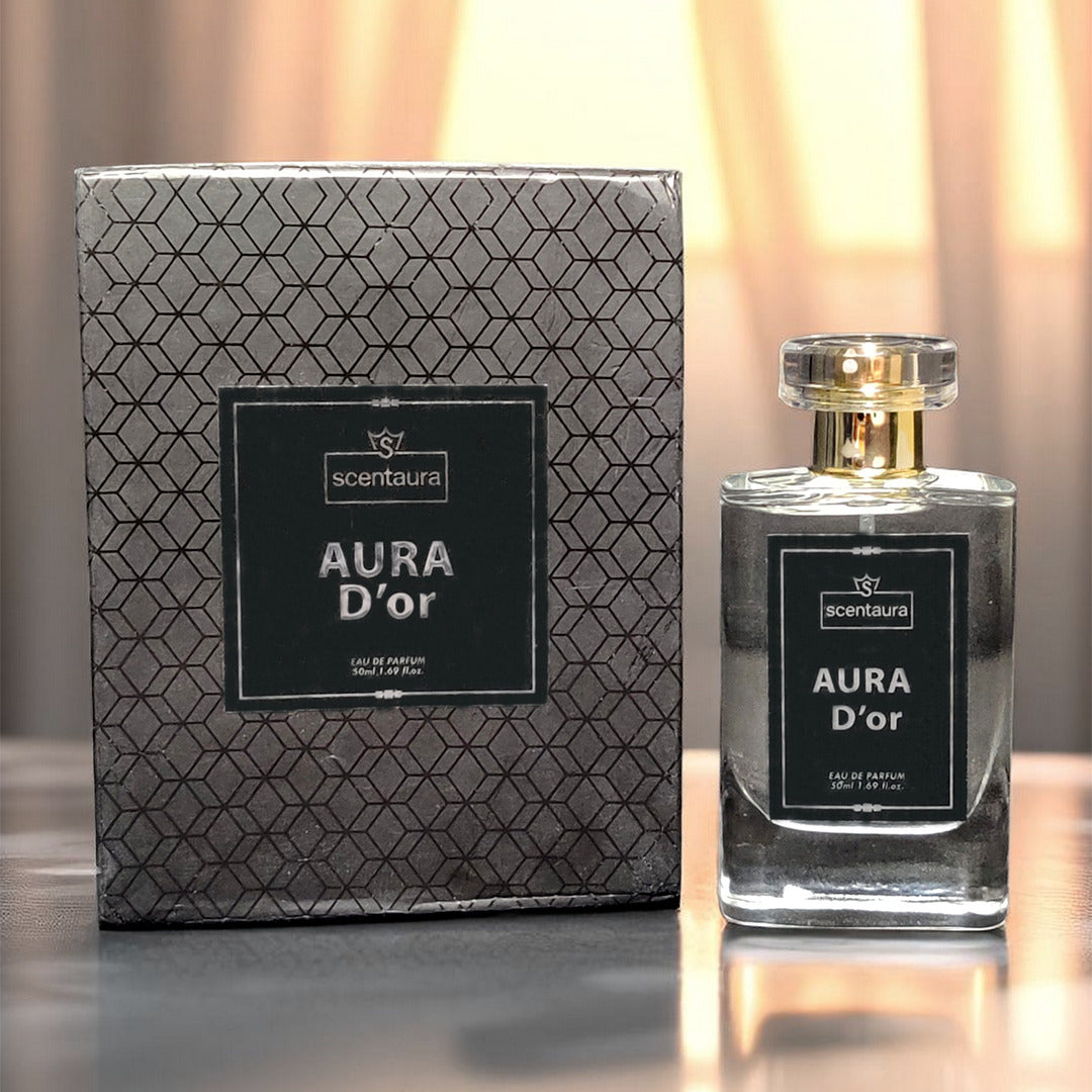 Scentura Aura D'or perfume bottle and packaging on a reflective surface with a blurred background